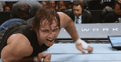 A Wrestler Is Laying On The Floor With His Mouth Open In A Wrestling Ring GIF
