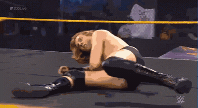 A Wrestler Is Laying On The Ground In A Ring With # 205Live Written On The Bottom GIF