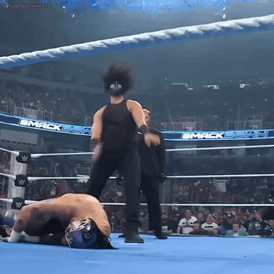A Wrestler Is Laying On The Ground In A Wrestling Ring With The Words Mack Down On The Walls GIF