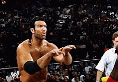 A Wrestler Is Pointing At Another Wrestler In A Wrestling Ring GIF