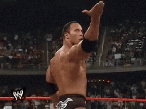 A Wrestler Is Raising His Fist In The Air In A Wrestling Ring . GIF