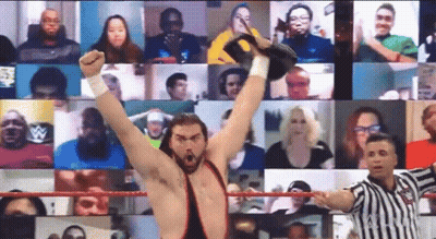 A Wrestler Is Raising His Fist In The Air In Front Of A Crowd While A Referee Looks On . GIF