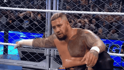 A Wrestler Is Sitting In A Cage During A Match . GIF
