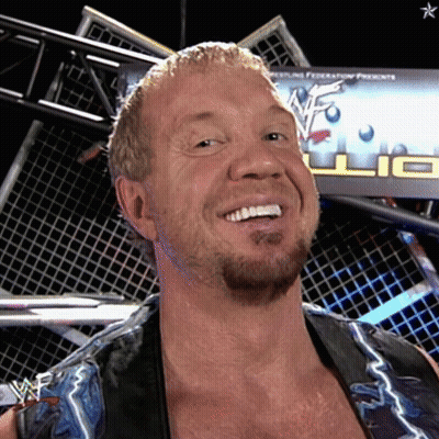 A Wrestler Is Smiling In Front Of A Wrestling Federation Sign GIF
