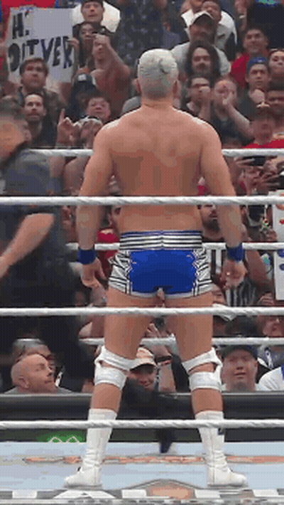 A Wrestler Is Standing In A Ring With A Crowd Behind Him And A Sign That Says Hi Oliver GIF