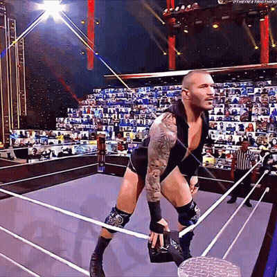 A Wrestler Is Standing In A Ring With A Referee In The Background GIF