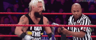 A Wrestler Is Standing In A Ring With A Referee . GIF