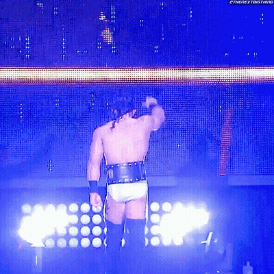 A Wrestler Is Standing In Front Of A Screen That Says The Nextbigthing GIF