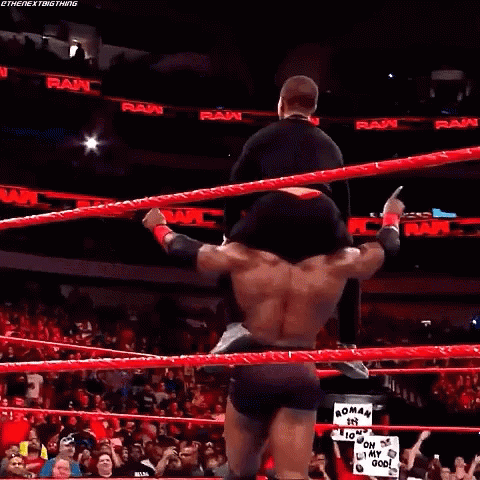 A Wrestler Is Standing In The Middle Of A Wrestling Ring Holding A Referee 'S Hand . GIF