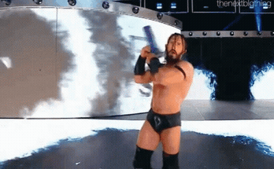 A Wrestler Is Standing On A Stage Holding A Sword In His Hand . GIF