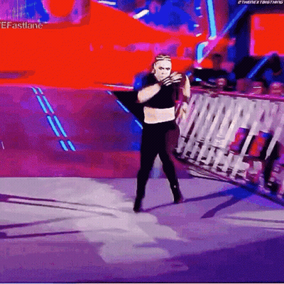 A Wrestler Is Standing On A Stage In Front Of A Crowd And Holding A Rope . GIF