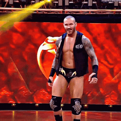 A Wrestler Is Standing On A Stage With A Ring In The Background .. GIF