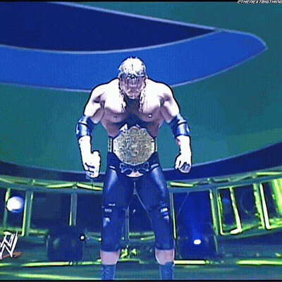 A Wrestler Is Standing On A Stage With A Wwe Logo In The Background GIF