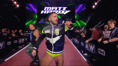 A Wrestler Is Walking Down A Red Carpet In Front Of A Sign That Says Matt Hprdy GIF