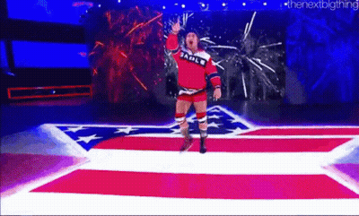 A Wrestler Is Walking Down A Red , White , And Blue Carpet On A Stage . GIF
