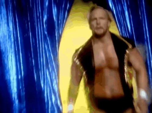 A Wrestler Is Walking Through A Blue Curtain In A Ring . GIF