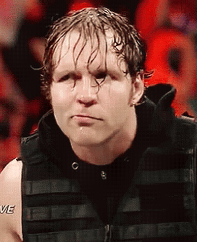 A Wrestler Is Wearing A Black Vest And Making A Funny Face While Standing In Front Of A Crowd . GIF