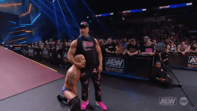 A Wrestler Kneeling Down In Front Of A Aew Banner GIF