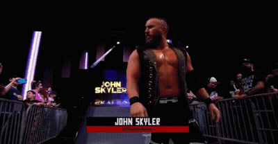 A Wrestler Named John Skyler Is Standing In Front Of A Crowd In A Wrestling Ring . GIF