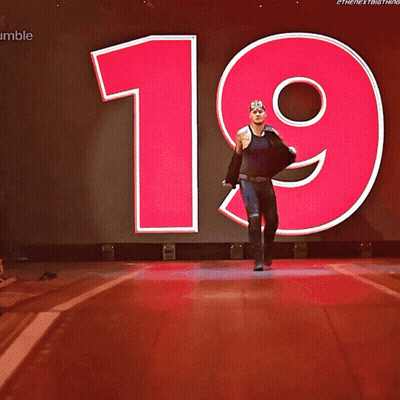 A Wrestler Named King Corbin Walks Down The Aisle In Front Of A Large Number 19 GIF