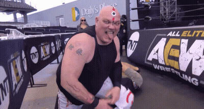 A Wrestler Stands In Front Of A Banner That Says All Elite Aew Wrestling GIF