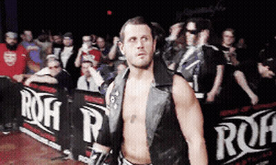 A Wrestler Stands In Front Of A Row Of Signs That Say Roh GIF