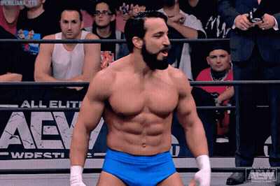 A Wrestler Stands In Front Of An Aew Sign GIF
