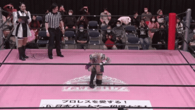A Wrestler Stands On A Pink Mat With A Sign That Says ' A ' On It GIF