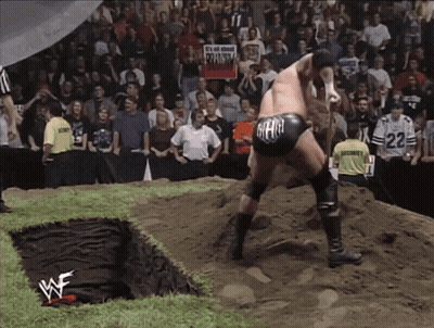 A Wrestler Wearing A Black Shorts With The Word Gear On It Stands In The Dirt GIF