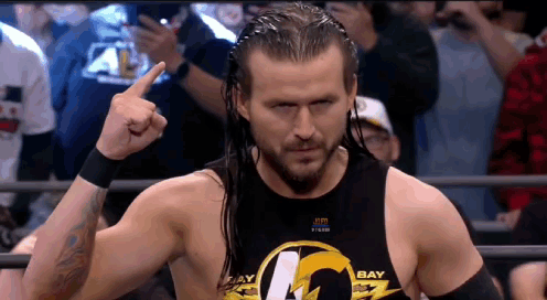 A Wrestler Wearing A Black Tank Top That Says Bay Is Giving The Middle Finger GIF