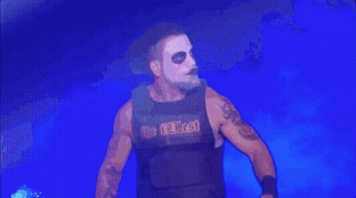 A Wrestler Wearing A Black Vest With The Word Lost On It Is Standing In Front Of A Blue Background . GIF