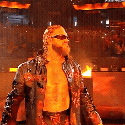 A Wrestler Wearing Sunglasses And A Leather Jacket Is Standing In Front Of A Crowd . GIF
