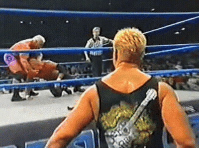 A Wrestler With A Guitar On His Back Is Standing In A Wrestling Ring . GIF