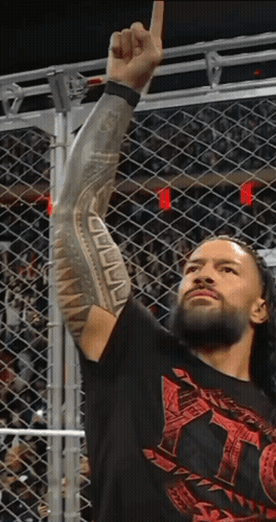 A Wrestler With A Tattoo On His Arm Holds Up His Fist In The Air GIF