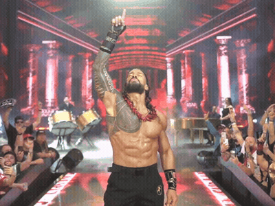 A Wrestler With A Tattoo On His Arm Is Giving A Thumbs Up In Front Of A Crowd GIF