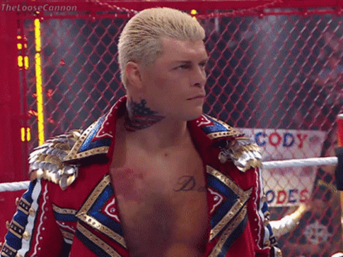A Wrestler With A Tattoo On His Neck Is Standing In Front Of A Fence That Says Cody GIF