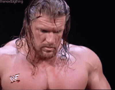 A Wrestler With Long Hair And A Beard Is Standing In A Ring Without A Shirt . GIF