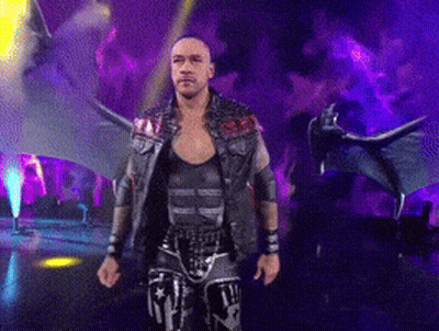 A Wrestler With Wings Is Walking On A Stage In Front Of A Dragon GIF