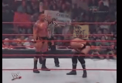 A Wrestling Match Is Being Held In A Ring With A Referee Standing Behind It . GIF