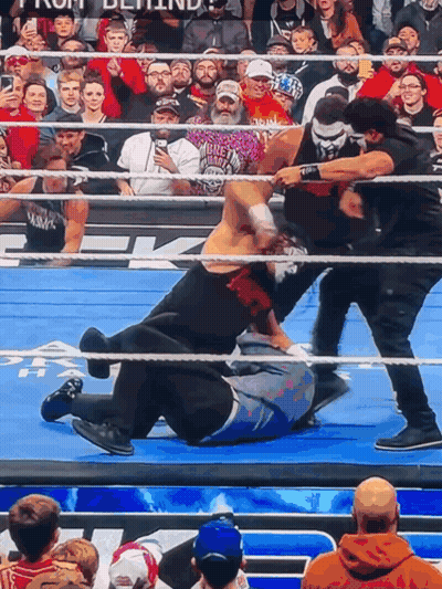 A Wrestling Match Is Going On In Front Of A Crowd With One Man Wearing A Shirt That Says ' Biker ' GIF
