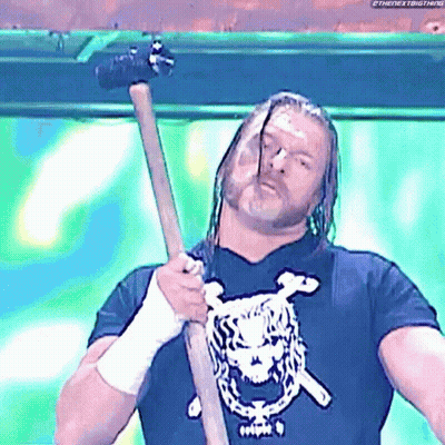 A Wrestling Wrestler Is Holding A Hammer In His Hand . GIF