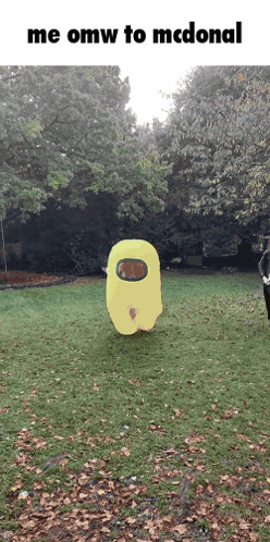 A Yellow Among Us Character Is Standing In The Grass GIF