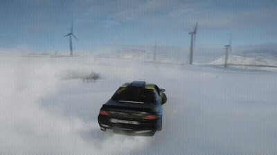 a yellow and black car is drifting in the snow with a wind turbine in the background