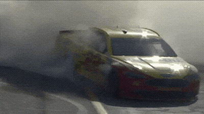 A Yellow And Red Race Car With Smoke Coming Out Of The Windshield GIF
