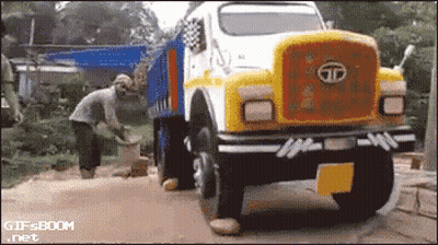 A Yellow And White Tata Truck With A Man Standing In Front Of It GIF