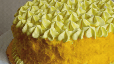 A Yellow Cake With Yellow Frosting And White Pearls GIF