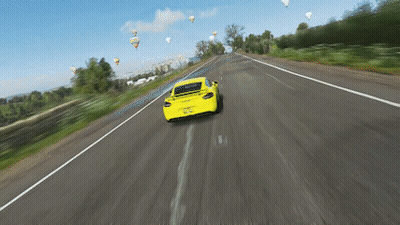 A Yellow Car Is Driving Down A Highway With Hot Air Balloons In The Background GIF