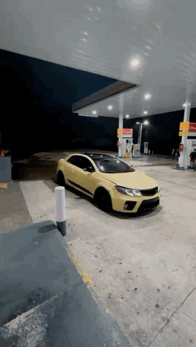 A Yellow Car Is Parked In Front Of A Gas Station GIF