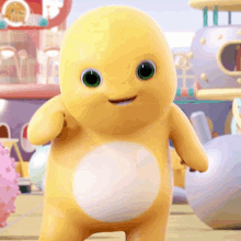 A Yellow Cartoon Character With Green Eyes And A White Belly Is Standing In Front Of A Toy Town . GIF