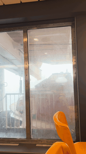 A Yellow Chair Sits In Front Of A Window Looking Out GIF